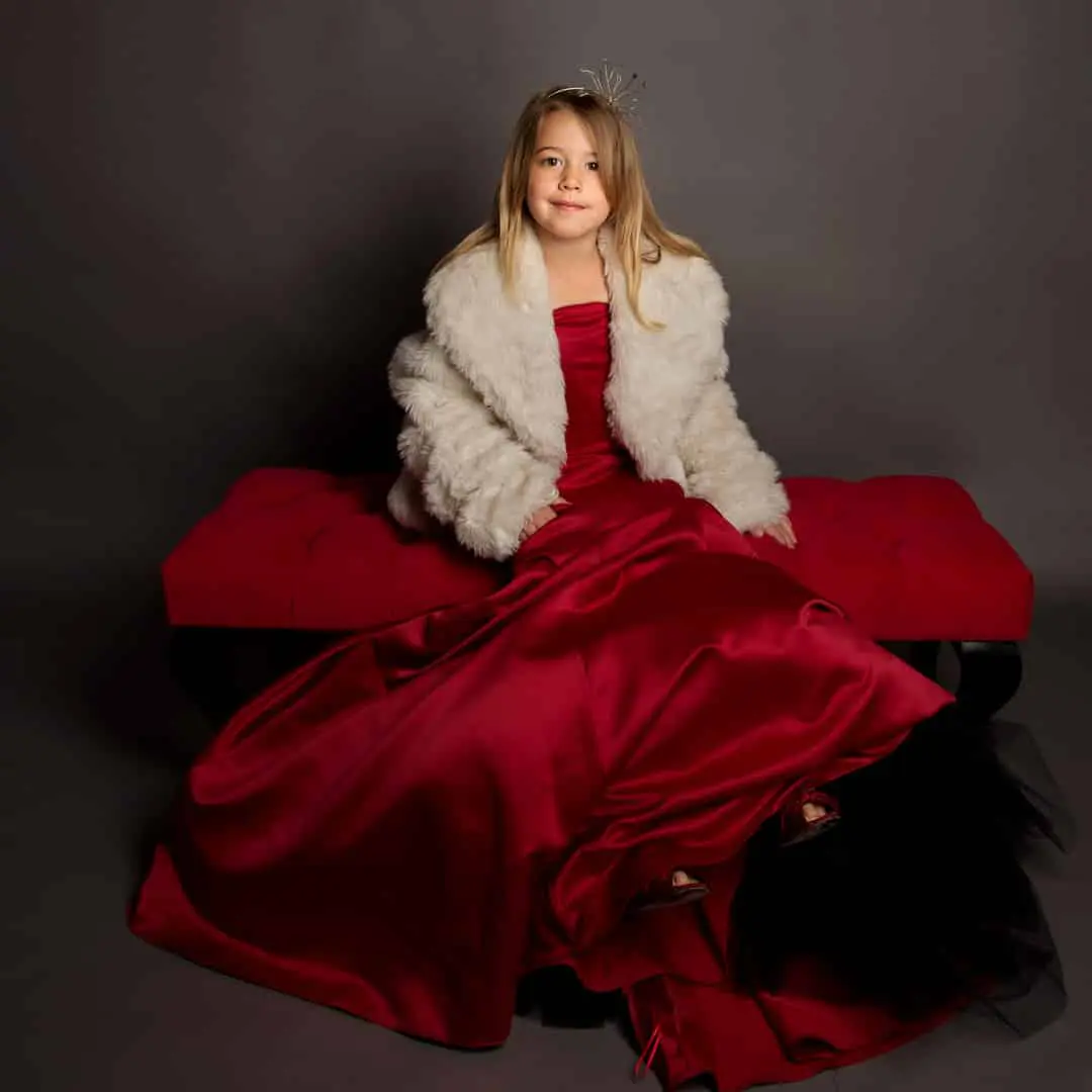 a little girl in her mum's red wedding dress