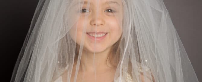 a little girl wearing her mum's wedding veil
