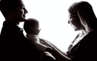 a mum and and dad pose in silhouette form in a black and white image