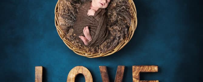A digital image of a sleeping newborn in a basket over wooden letters that spell love