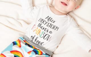 a little boy looking up at the camera in a rainbow themed outfit