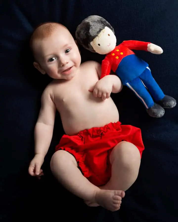 a little boy poses with his favourite guardsman toy against a navy blue backdrop