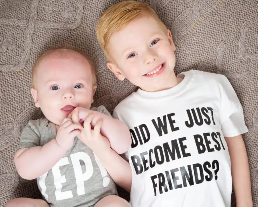 Two children lie on the floor looking up wearing matching tshirts