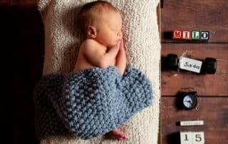 a sleeping newborn on my miniature dark wood bed prop