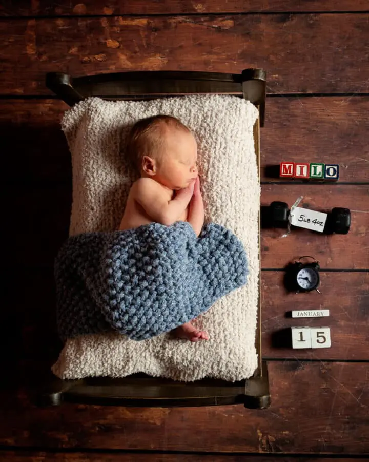 a sleeping newborn on my miniature dark wood bed prop