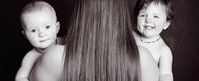 a lady with her back to the camera holds a twin on either side of her