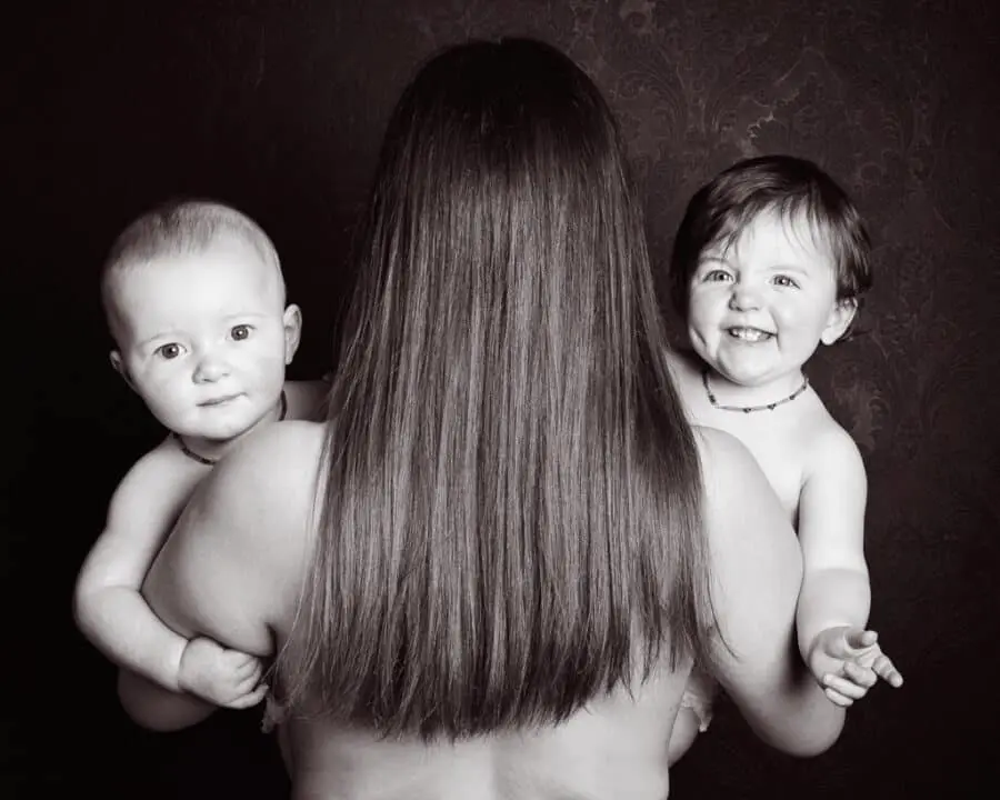 a lady with her back to the camera holds a twin on either side of her