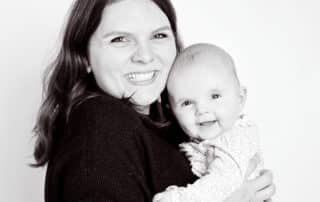 a mum poses with her daughter in a black and white professional portrait studio image against a white background