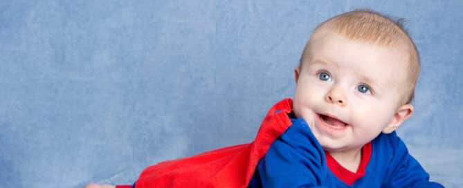a little boy in a superman outfit poses at a professional photo shoot