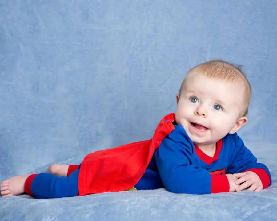 a little boy in a superman outfit poses at a professional photo shoot