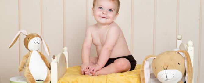 a little boy on a bed with Nutbrown Hare soft toys and props