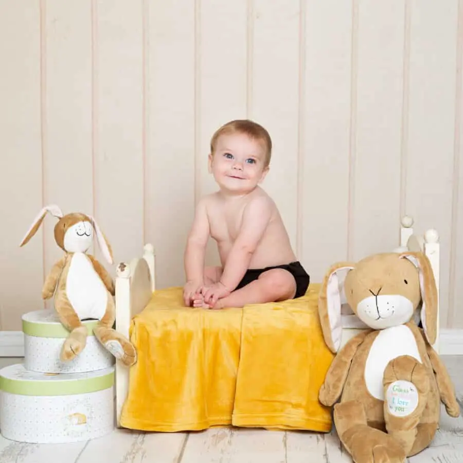 a little boy on a bed with Nutbrown Hare soft toys and props