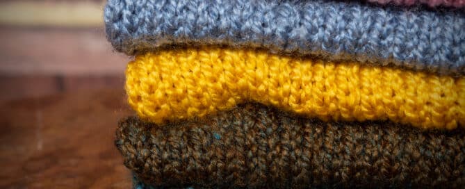 a stack of hand knitted blankets for newborn and baby photography