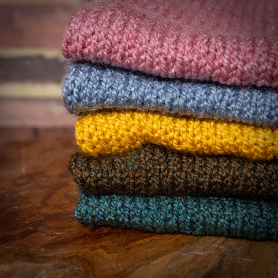 a stack of hand knitted blankets for newborn and baby photography