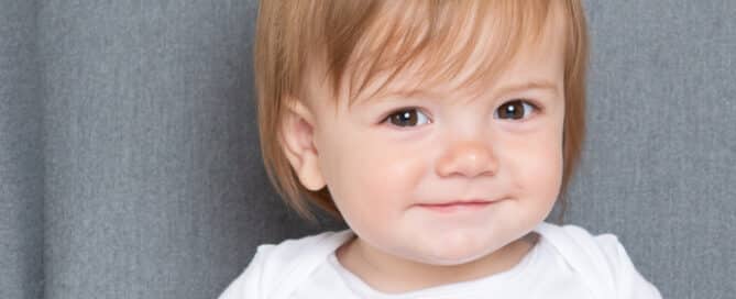 a little boy in a vest that reads Albie smiling for the camera at a professional photo shoot