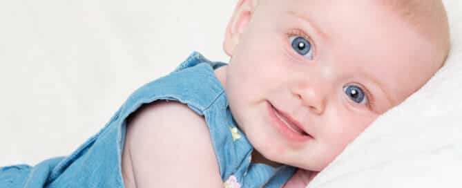 a bright blue eyed girl looks into the camera lying on her tummy