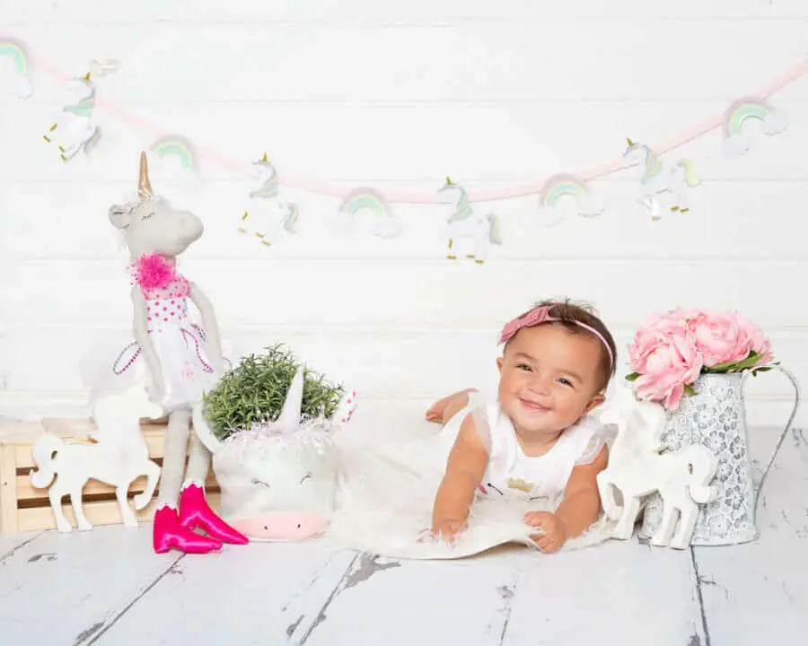 vBaby Photography East Grinstead West Sussex a little girl poses on her tummy with unicorn props