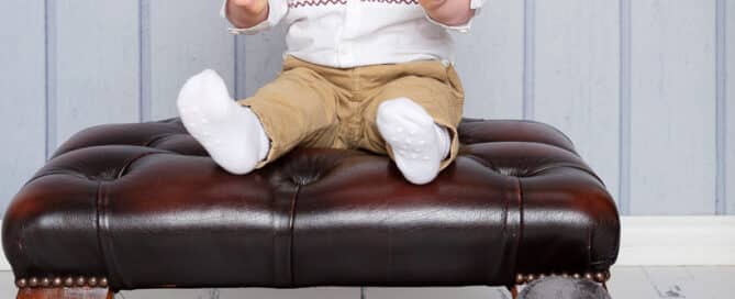 a little boy sits on a stool laughing with his favourite guardsman toy