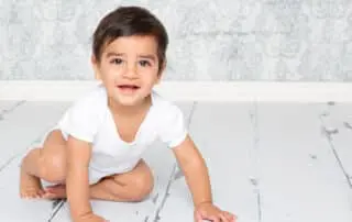 a little boy in a white vest photographed against a blue damask background