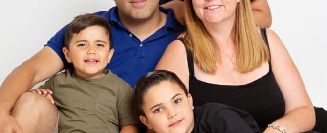 a family of two adults and three boys pose for a professional family portrait
