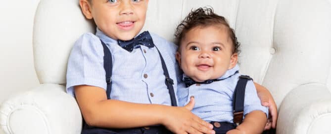 two brothers pose for professional family portraits in matching bow ties and braces