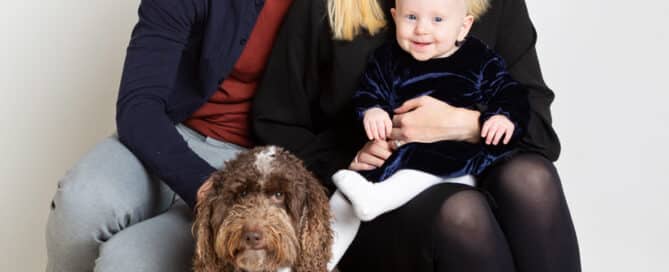 a family of a mum, dad and baby girl pose with their family dog