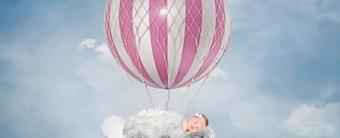 a digital image of a newborn in a pink hot air balloon in a blue sky