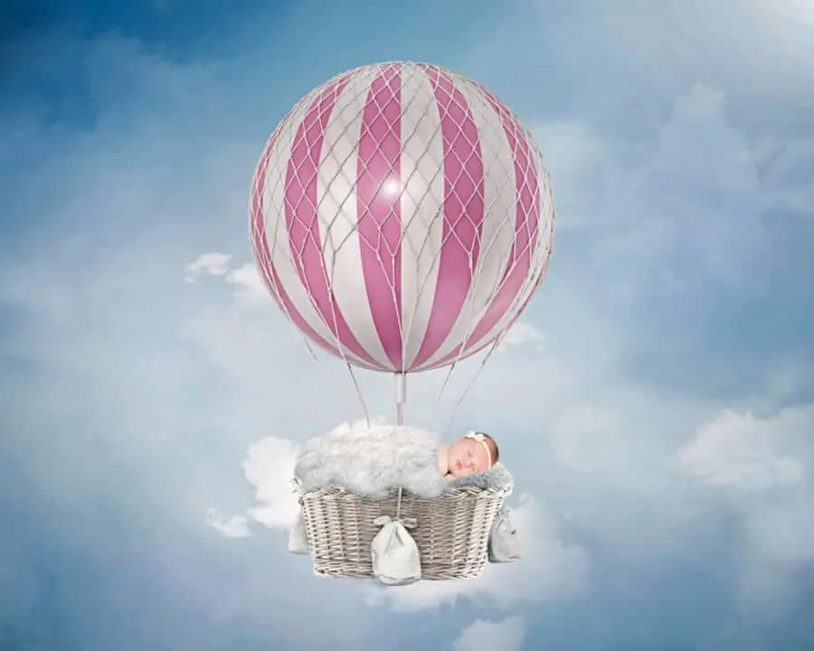 a digital image of a newborn in a pink hot air balloon in a blue sky
