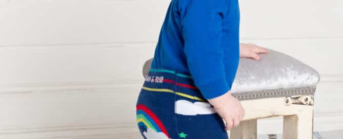 a little boy in rainbow themed leggings and a blue top
