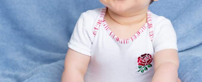 a little boy in a rugby vest against a blue blanket
