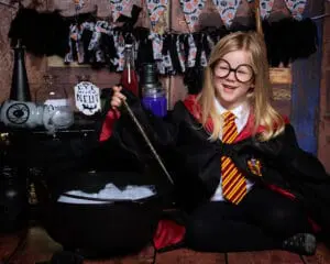 Halloween Mini Photo Shoots East Grinstead West Sussex a little girl dressed in a Harry Potter outfit sitting by a cauldron at a studio photo shoot
