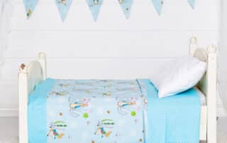 a miniature white bed with my peter rabbit themed quilt and bunting