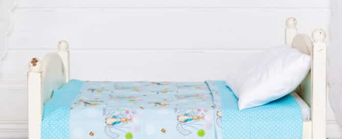 a miniature white bed with my peter rabbit themed quilt and bunting