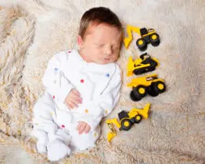 a sleeping newborn surrounding by digger toys