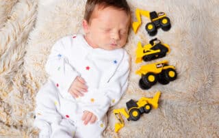 a sleeping newborn surrounding by digger toys