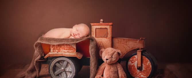 a digital image of a newborn sleeping in the back of a toy truck