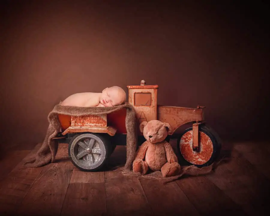 a digital image of a newborn sleeping in the back of a toy truck