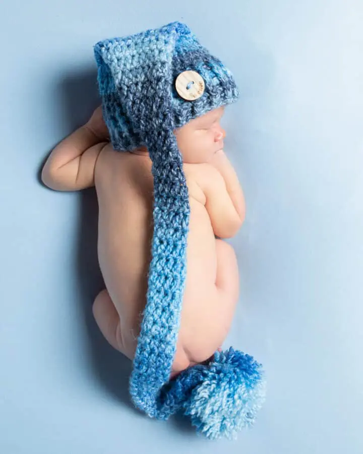 Newborn Photography East Grinstead West Sussex A newborn baby viewed from the top while lying on their tummy wearing a long tailed blue hat
