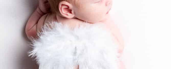 a view from above of a newborn asleep tucked up with a pair of tiny angel wings on their back