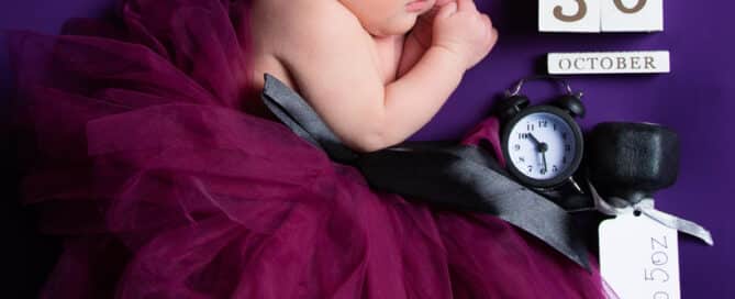 a newborn in a purple tutu on a purple blanket