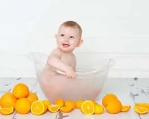 a little boy in a milk bath surrounded by oranges at a first birthday portrait session