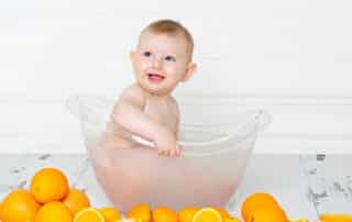a little boy in a milk bath surrounded by oranges at a first birthday portrait session