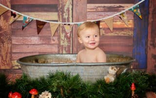 a little boy in a tin tub with woodland creature props