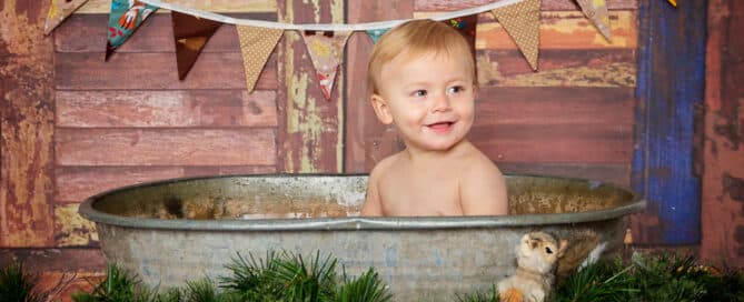 a little boy in a tin tub with woodland creature props