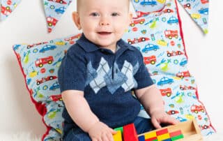 a little boy is holding a wooden truck and posing for his photo at a professional photo shoot