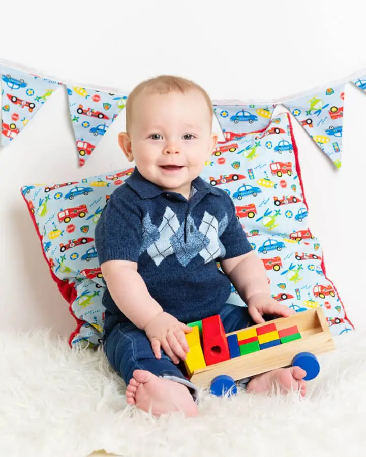 a little boy is holding a wooden truck and posing for his photo at a professional photo shoot