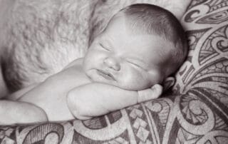 a little baby sleeps in dad's tattooed arm