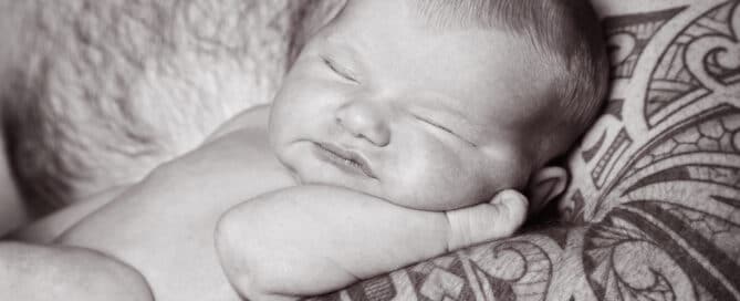 a little baby sleeps in dad's tattooed arm
