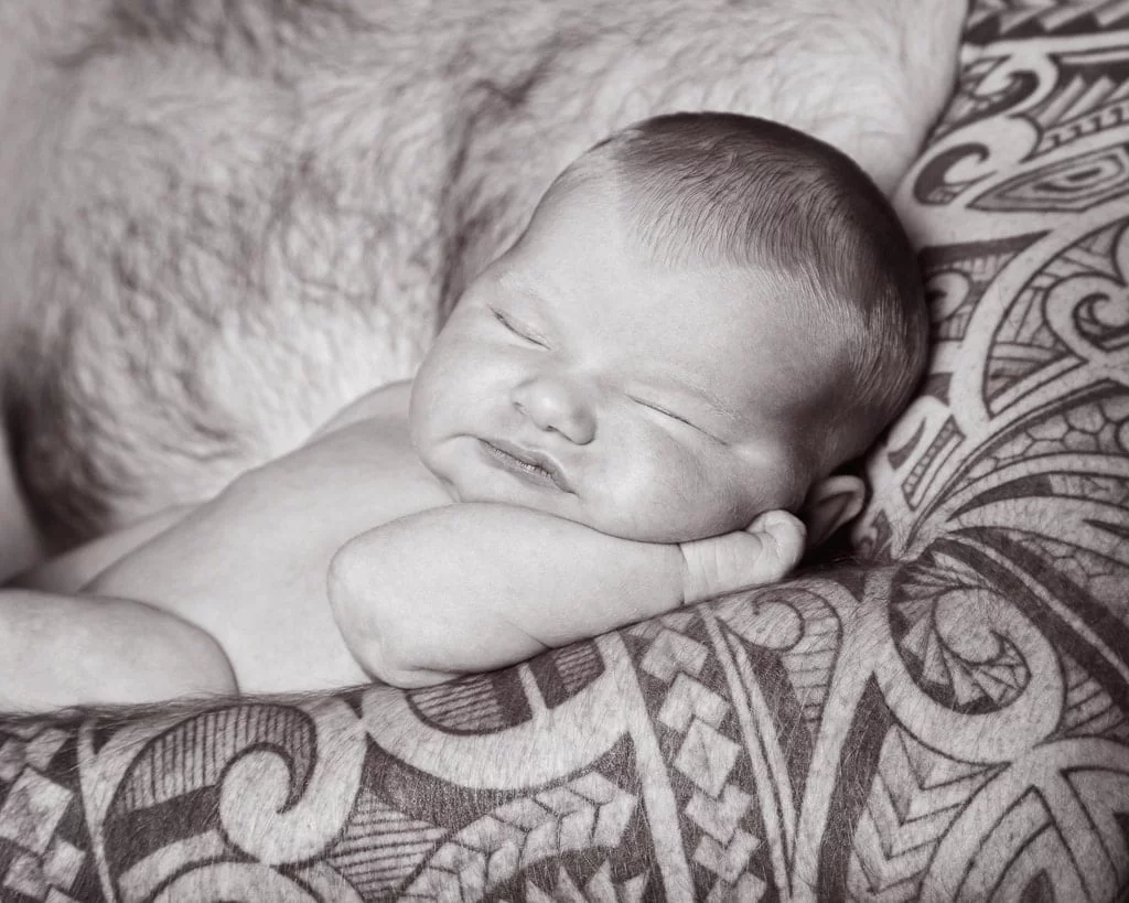 a little baby sleeps in dad's tattooed arm
