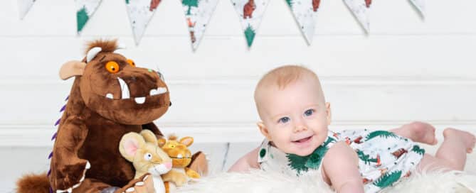 a little boy with a gruffalo toy in a gruffalo themed romper